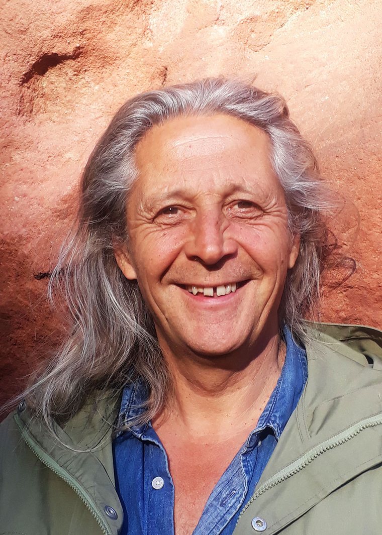 Porträt von Dirk M. Lehmann, lächelnd vor rotem Fels