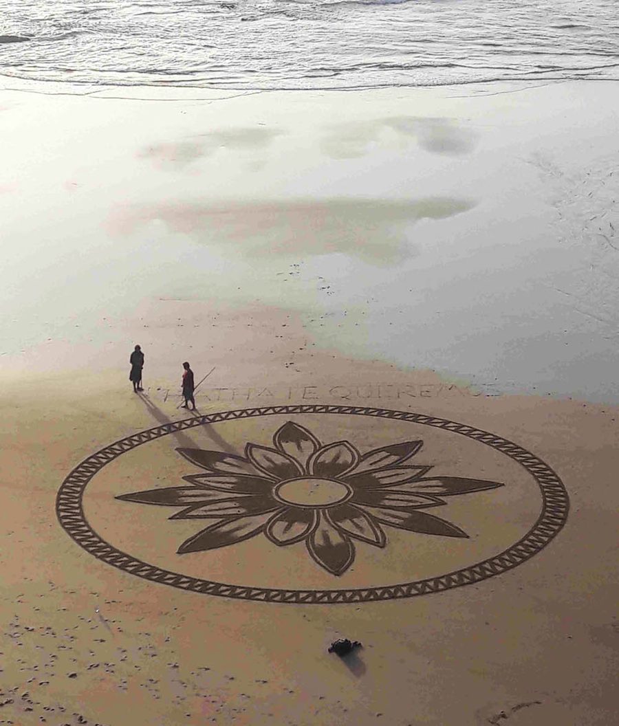 Großes Sandmandala am Strand, zwei Menschen stehen am Rand der Zeichnung